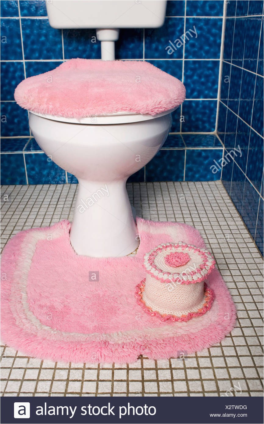 a toilet with fluffy pink seat cover and rug X2TWDG